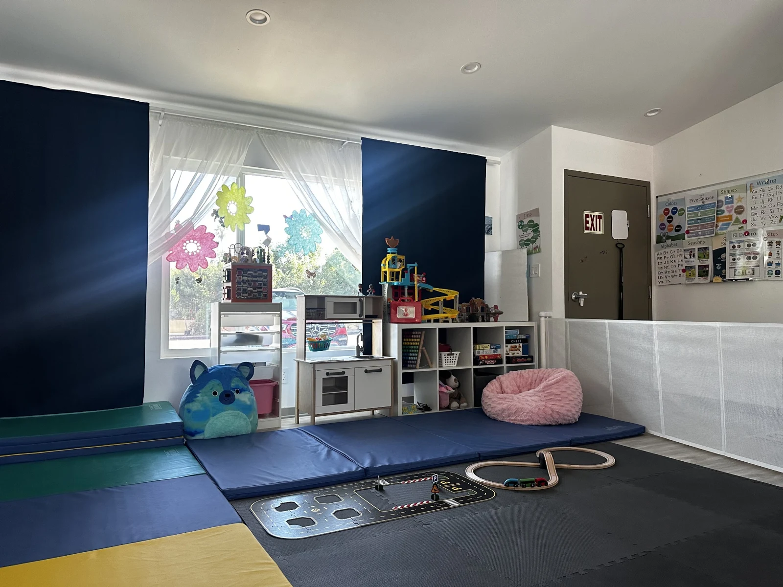 Merrymoon play area with colorful mats, a toy kitchen, and activity shelves