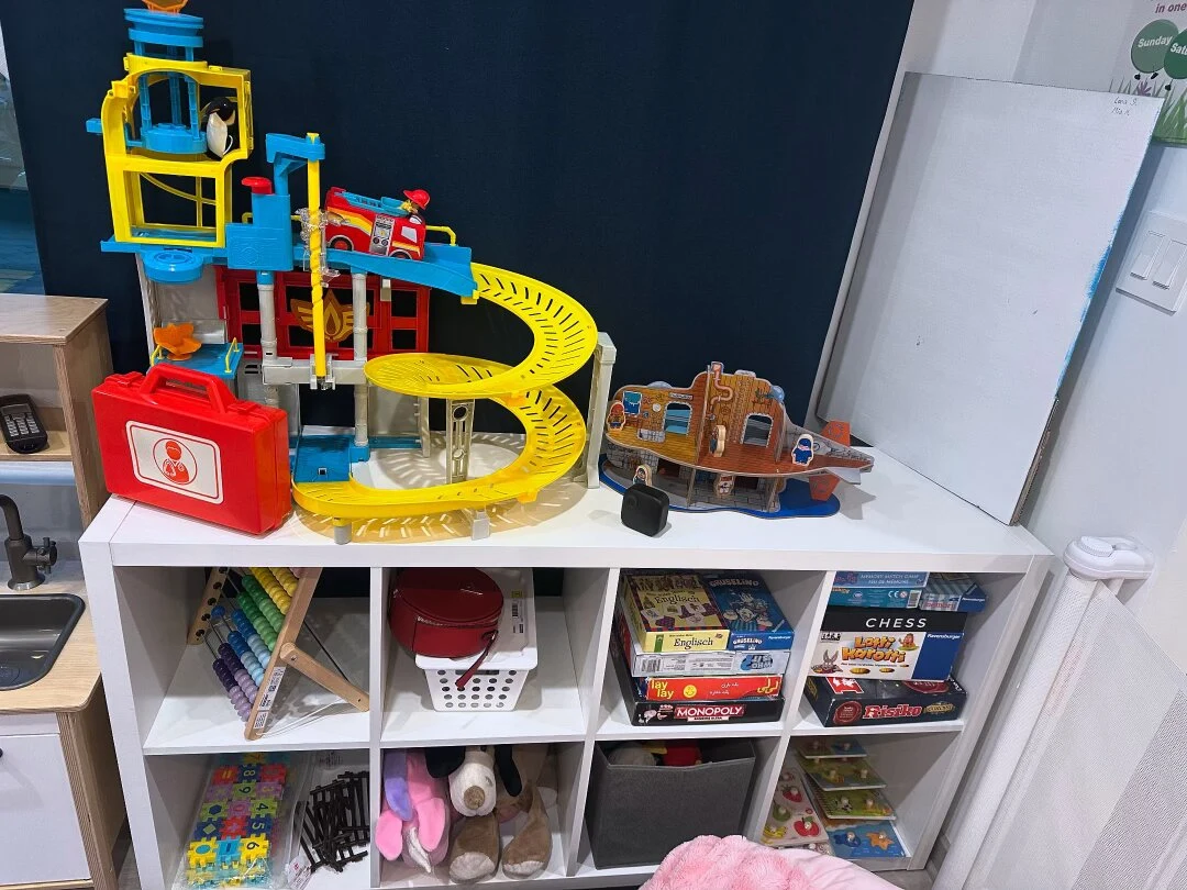 Toy garage, games, and books on a classroom shelf